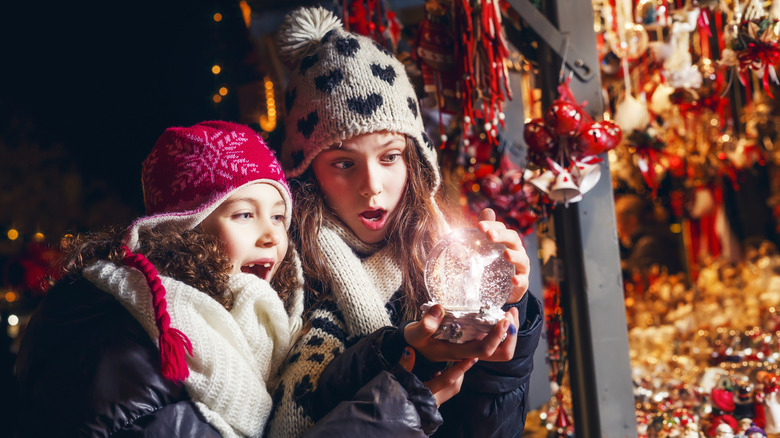 Girls looking into a snow globe at a Christmas market