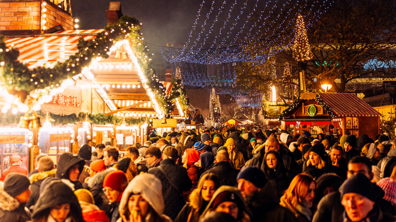 Crowded Christmas market at night, illuminated by decorative lights