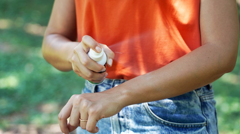 Girl spraying insect repellent on arm