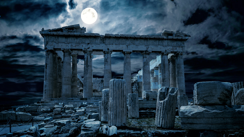 The Acropolis at night against the backdrop of a large, bright moon.