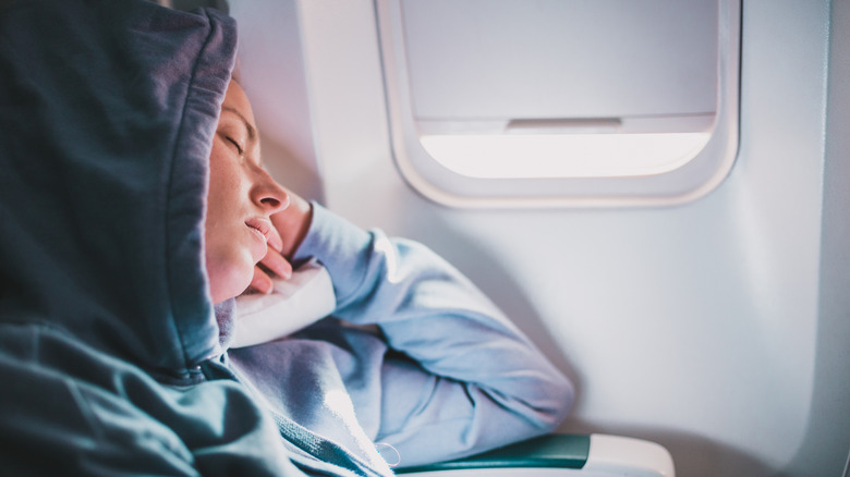 Person wearing a hoodie while asleep on a flight