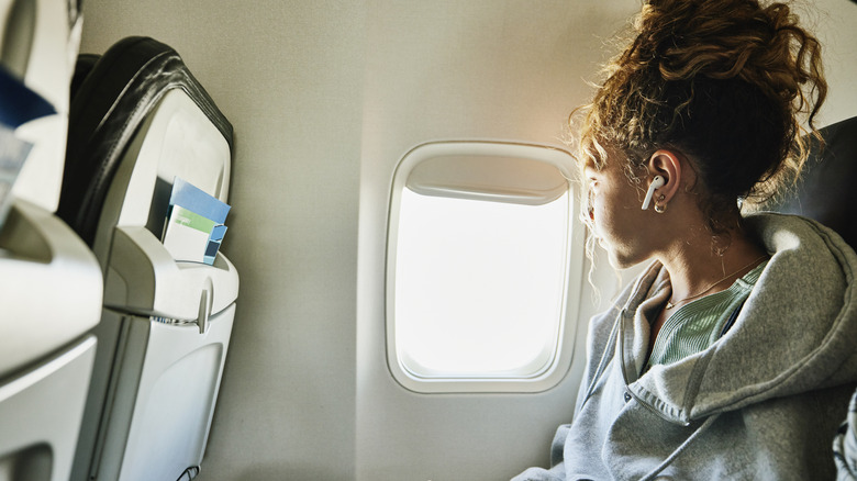 Woman on airplane wearing ear buds