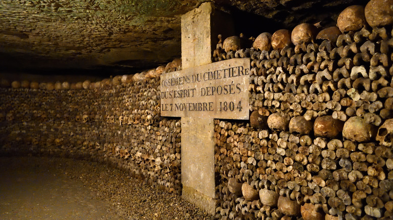 Stacks of bones alongside a cross in the Paris catacombs, France.