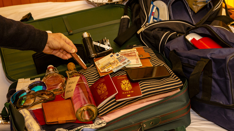 Someone packing a bottle of alcohol in their luggage