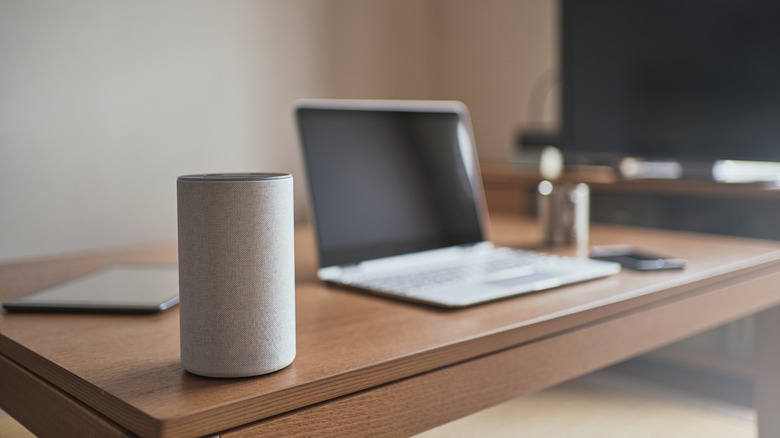 A bluetooth speaker on a desk in front of a computer