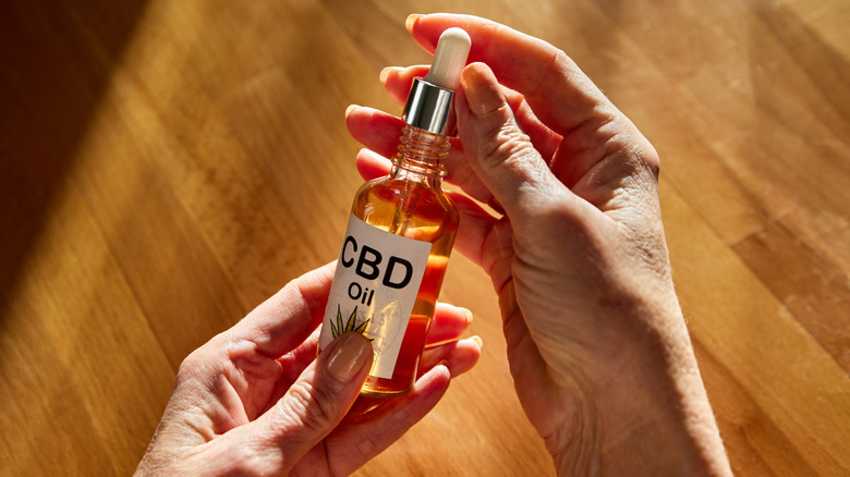 Hands holding CBD oil bottle