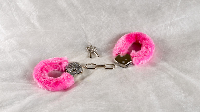 Fuzzy pink handcuffs on a white background