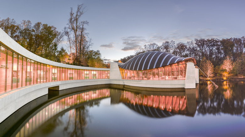 The Crystal Bridges Museum of American Art is reflected in the pond at dusk.