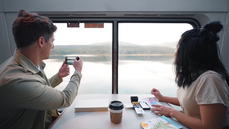 Two travelers look out a train window at Glacier National Park