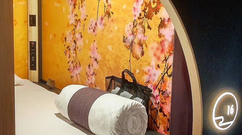 Capsule at Resol Poshtel, Tokyo with walls decorated with a cherry blossom design