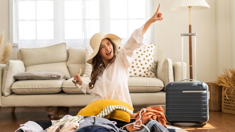 happy woman traveler unpacking a suitcase