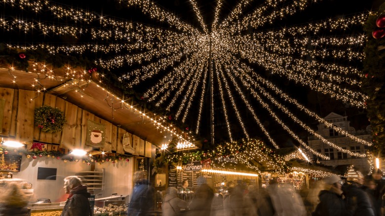 People explore the Lübecker Weinachtsmarkt, a Christmas market in the northern German city of Lübeck, while holiday lights twinkle overhead