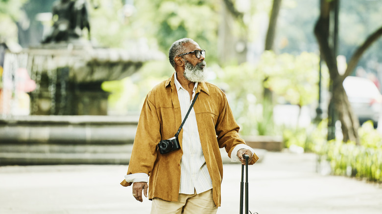 older man walking with camera and suitcase