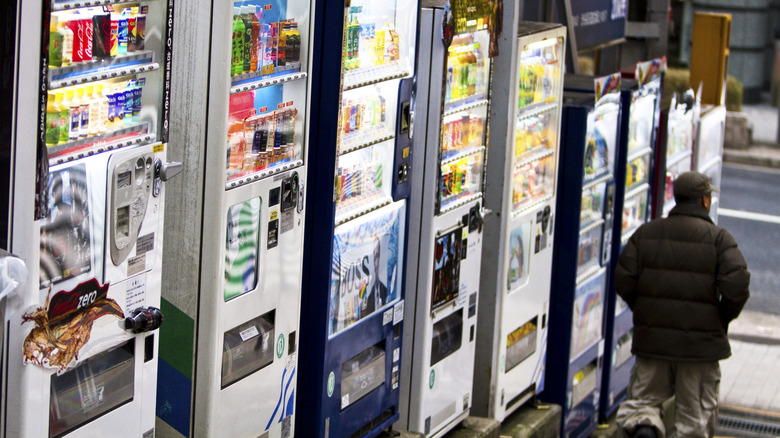 Pedestrian walking by a row of vending machines in japan