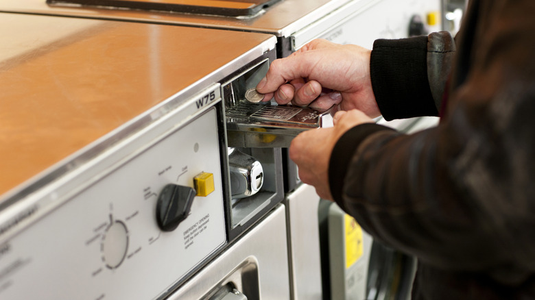 Putting coins in laundry machine