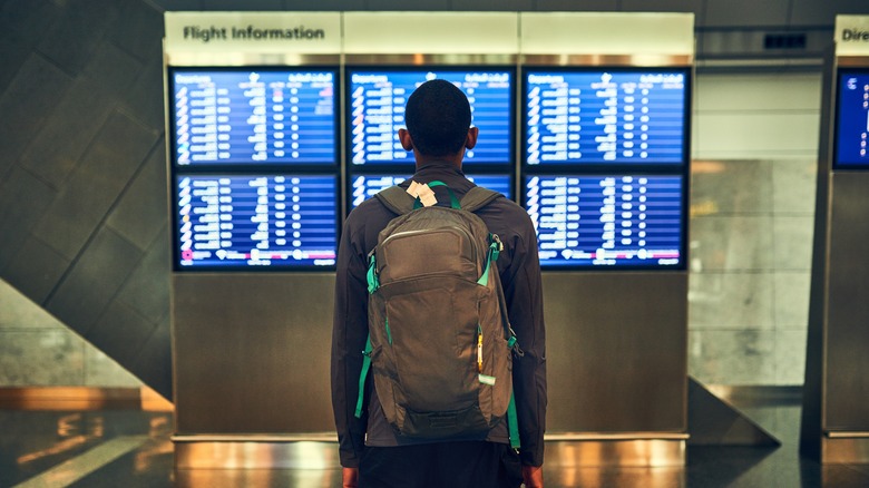 Man looking at board with flight departure and arrival information