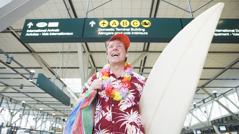 Man at airport holding surfboard