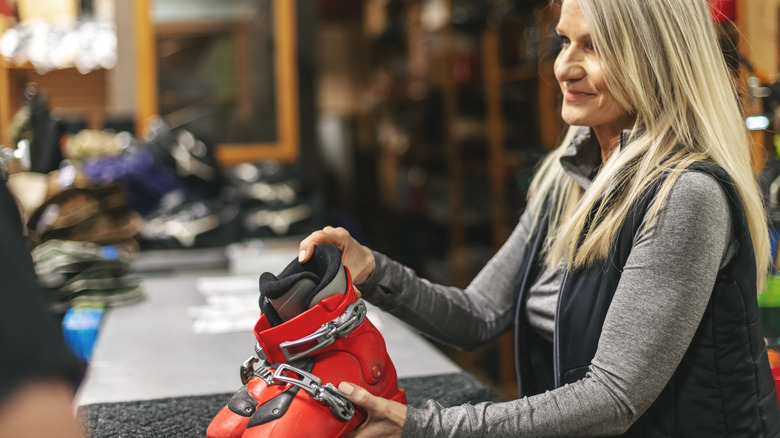 Woman handing over ski boots at rental counter