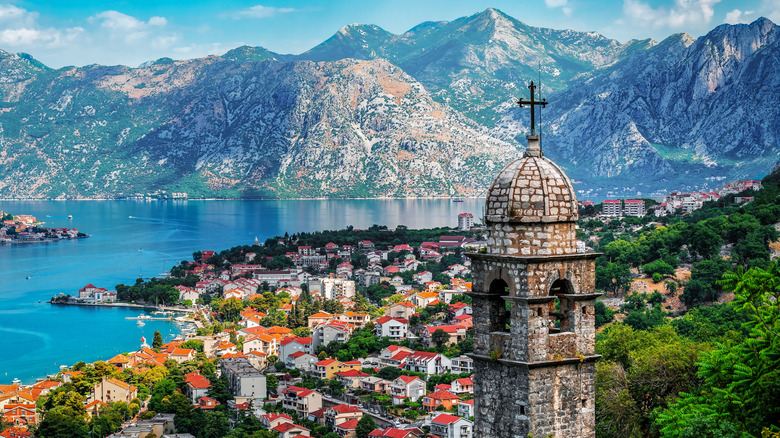 Stone bell tower and red-roofed village houses on the sea framed my mountains