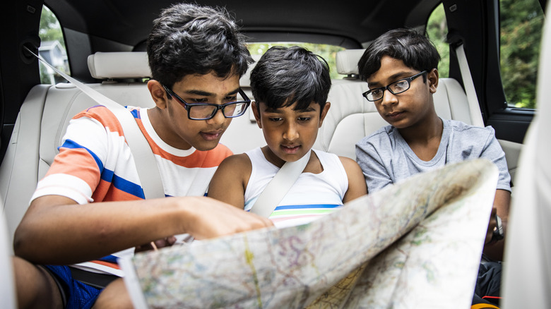 Boys looking at a map in a car, plotting their road trip