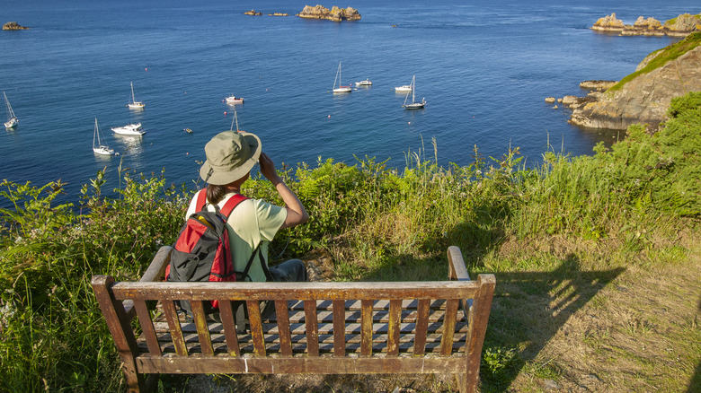 Woman sitting on a bench overlooking the sea in Sark