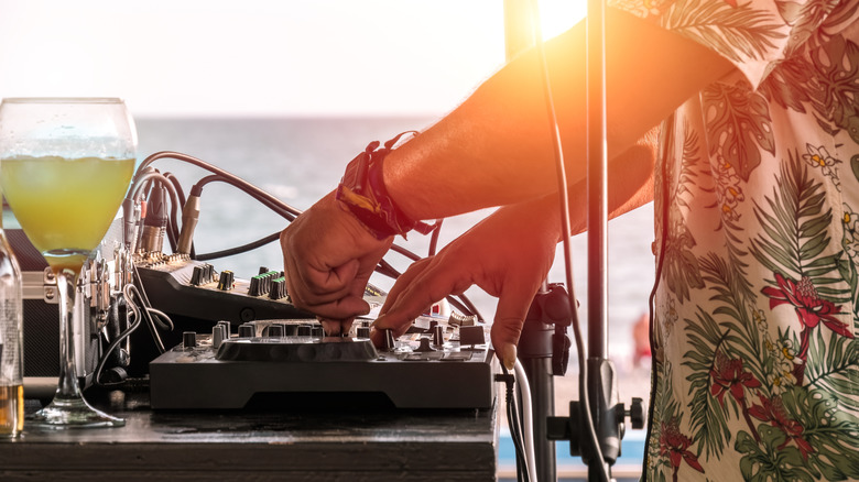 DJ with a drink by the beach at sunset