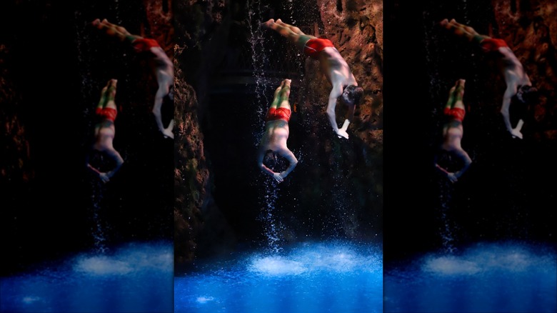 Two cliff divers plunge into a pool at Casa Bonita