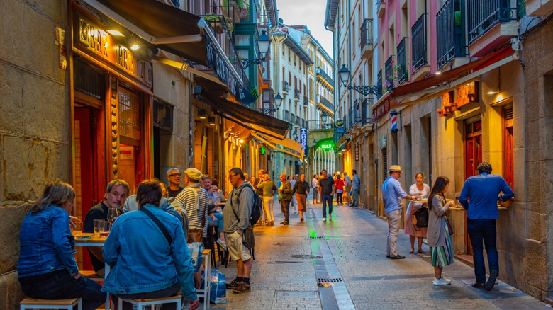 A narrow street in San Sebastián, Spain, with people dining outside