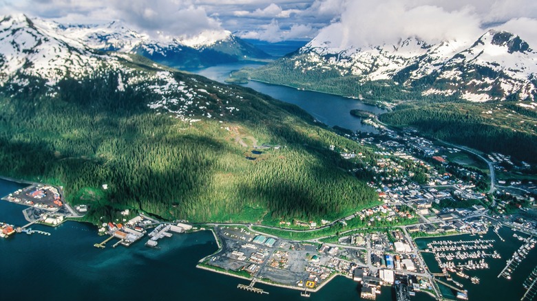 An aerial view of a small town on the coast with mountains in the background