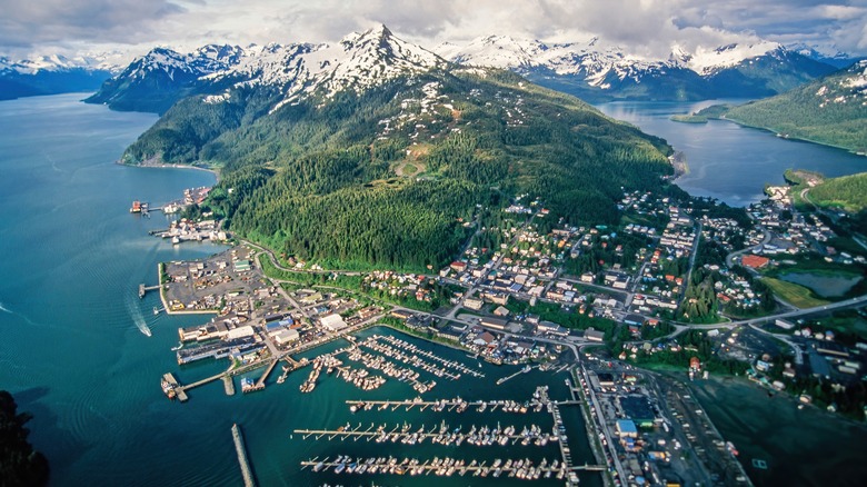 An aerial view of a small town on the coast with mountains in the background