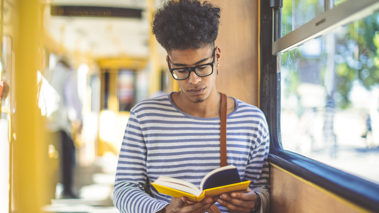 Man reading a book on a train