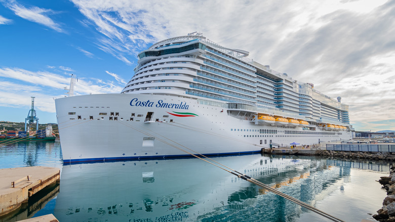 Costa Smeralda cruise ship docking at port with reflection in water and clouds