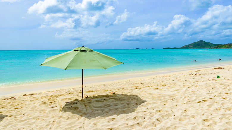 View of green umbrella in the sand at Valley Church Beach with water in backdrop