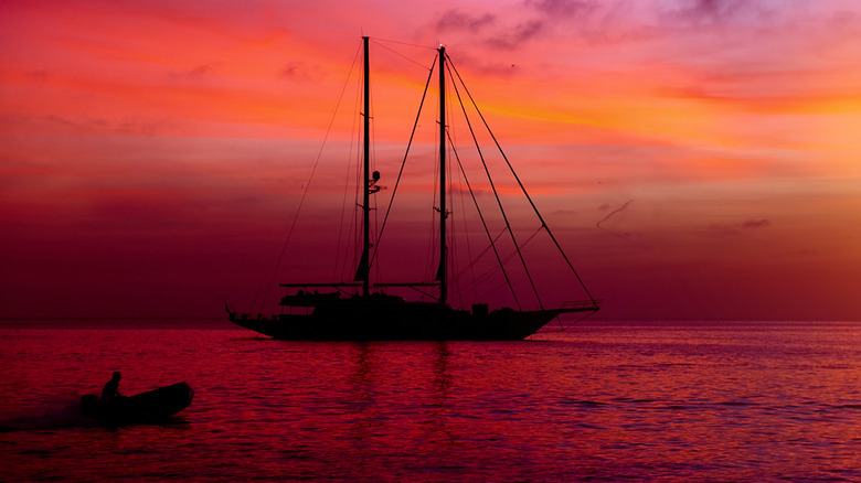 Red sunset in the backdrop of a large sailboat at Cala Saona