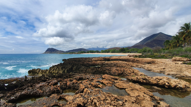 The rocky Mermaid Cave in Oahu, Hawaii with mountains in the background