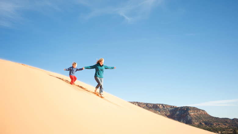 Two people running down dunes at Coral Pink Sand Dunes