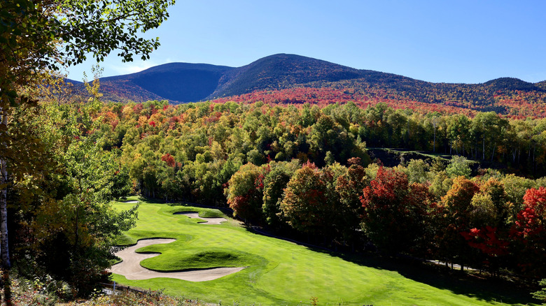 Maine golf course in fall surrounded by trees and hills