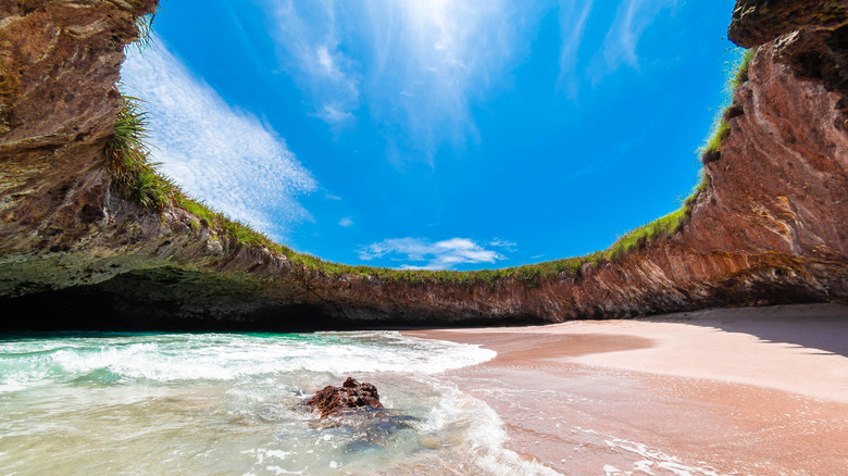 Hidden beach surrounded by rock walls with a hole to the sky above in Nayarit