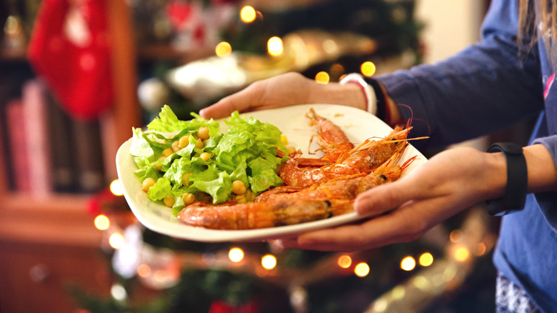 Person with a plate of shrimp and lettuce in Santander, Spain