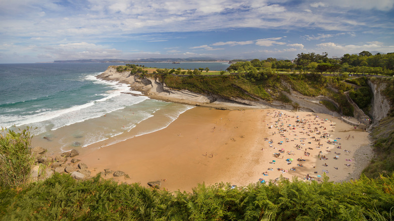 People lounging on the golden sand at Mataleñas Beach, Santander, Spain