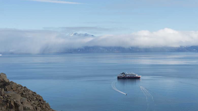 Small ship near Greenland with cloud-covered mountain in the background