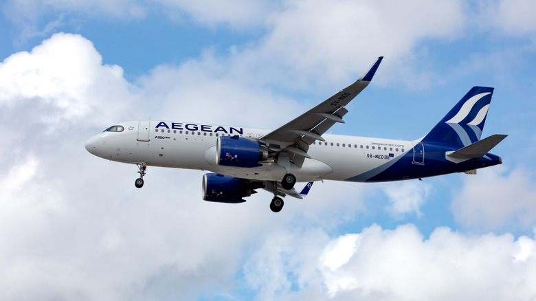 Aegean Air plane soars through partly cloudy skies