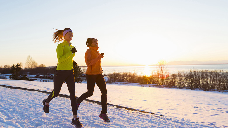 Joggers in Anchorage, Alaska running on a snowy path on a sunny day