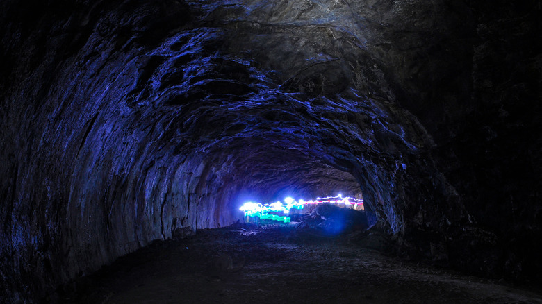 Long exposure photo in a pitch black cave showing streams of light from hiker's headlamps as they pass through and illuminate the cave walls