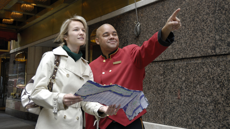 Doorman helping direct woman with map