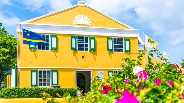 Yellow facade of the Landhuis Chobolobo with flowers in front