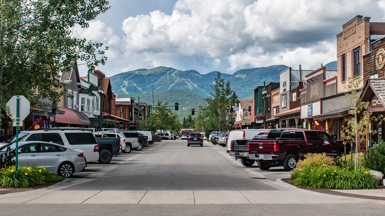 A street view of downtown Whitefish, Montana, with cars, buildings and mountains