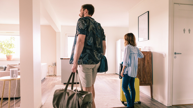 People bringing luggage into an Airbnb