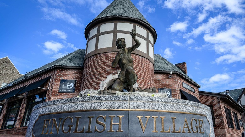 A shot of the English Village statue in Mountain Brook, Alabama, features the European-styled architecture behind and a blue sky above.