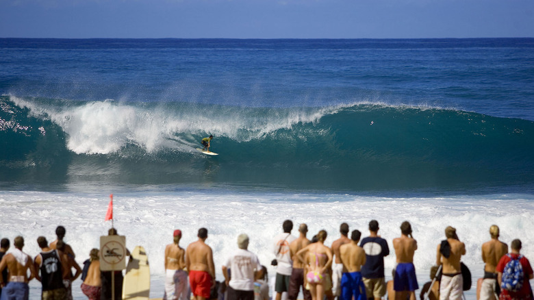 Viewers watch as a surfer takes a wave at Pipeline on Oahu